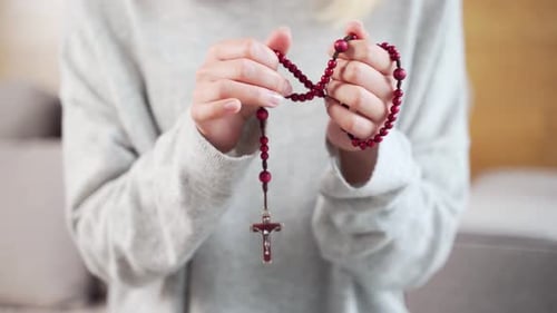 Christian rosary with close up Female. A woman's hands pray in a church or temple or at home. Prayer