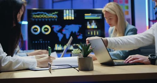 Business Professionals Analyzing Data at Night in Modern Office