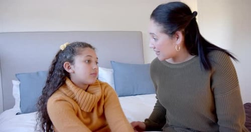 Girl and Woman Embrace on Bed Indoors