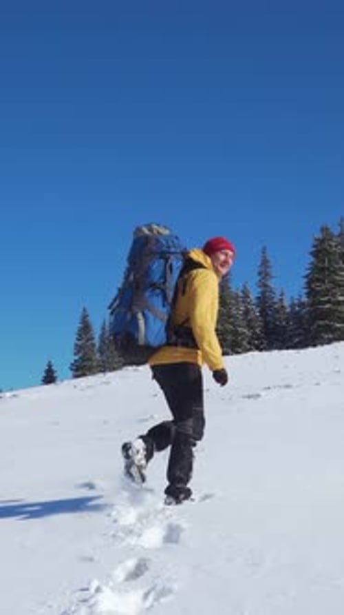 Adventurous Hiker Ascends Snowy Hill in Winter
