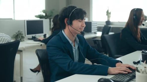 Asian Operators are wearing headphone working in workplace .