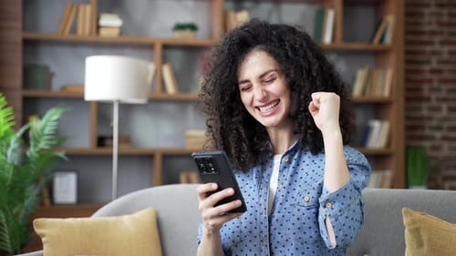Happy Woman Using Smartphone on Couch at Home