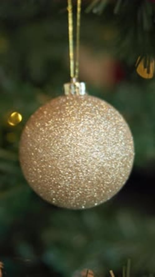 Sparkling Gold Christmas Bauble Hanging on Christmas Tree