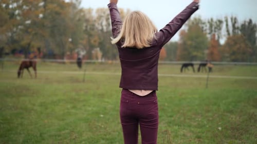 Joyful Teenage Girl Spinning Smiling on Autumn Meadow with Horse Barn at Background