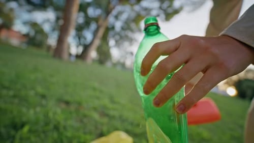 Activista sostiene de la mano una botella de plástico en Cleanup Park Closeup Eco Volunteer