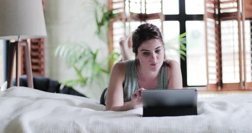 Woman Using Tablet While Lying on Bed