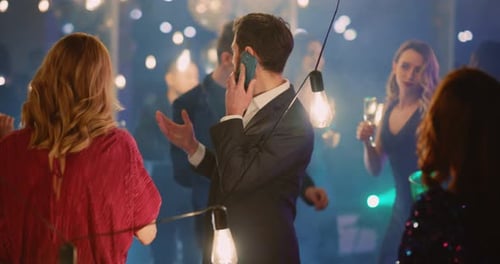 Jovem empresário caucasiano preocupado passando festa corporativa com colegas ligando para celular