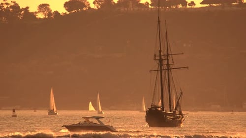 Majestic Tall Ship Sailing Through Golden Mist at Coastal Sunset