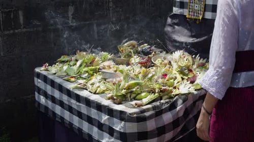 Ofrenda balinesa de Canang con flores e incienso sobre la mesa del santuario del templo