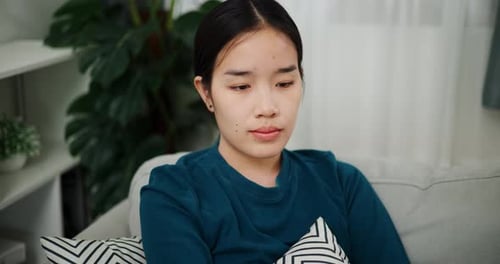 Young Woman Sits on Couch at Home