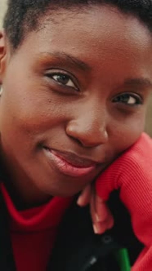 Vertical video, Close up, smiling young woman looking at camera sitting on bench on city street