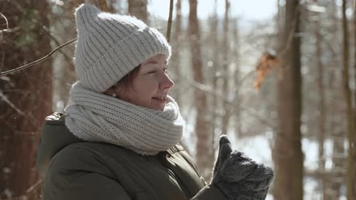 Woman in Mittens Looks at Sparkling Snowflakes with Smile in Frosty Winter