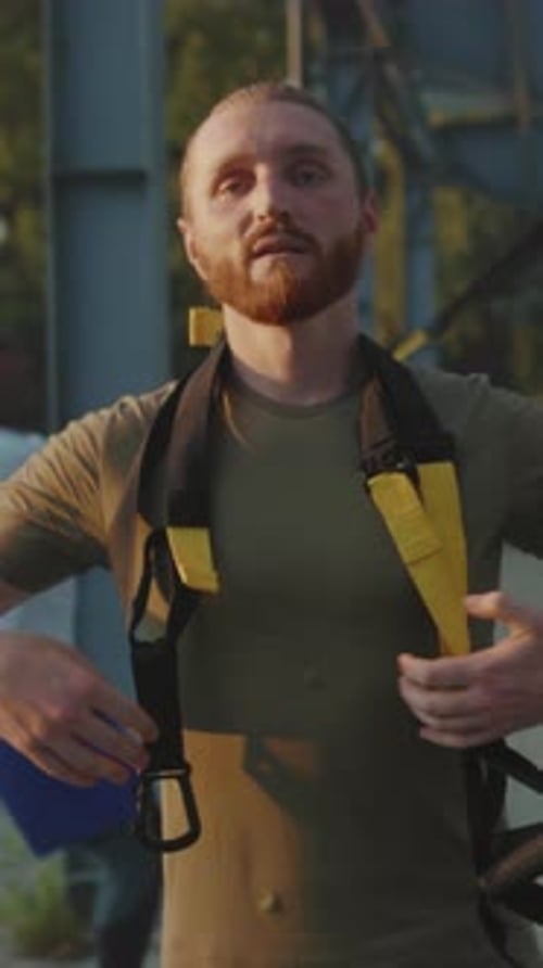 Industrial Technician Reviews Safety Harness Details Man with Safety Gear Examines Metal Structure
