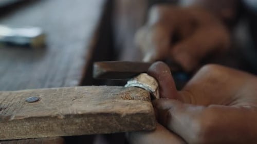 Juwelier feielt einen Silberring auf einer Holzstütze