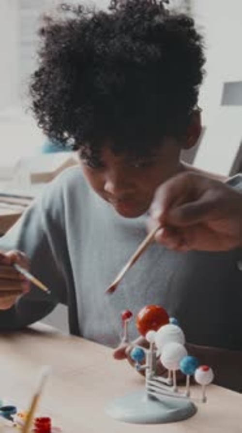 Boy Painting Solar System Model at Home
