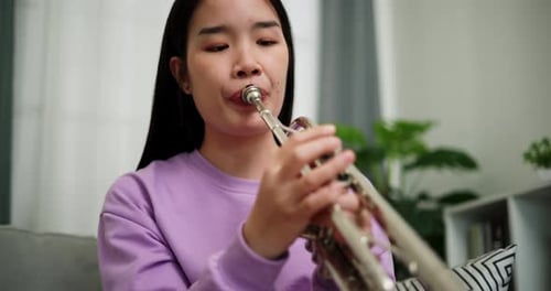 Young Woman Plays Trumpet at Home Close Up
