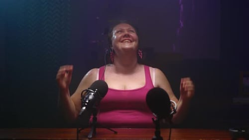 Woman Smiling in Front of Microphones in Studio