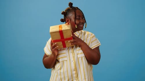 Surprised Female Examining Gift Box in Hands in Studio
