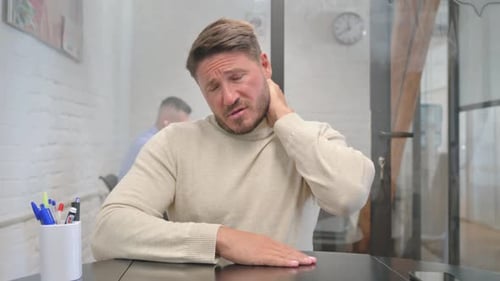 Man Massaging Stiff Neck at Desk