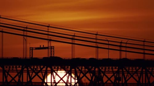 Silhouette der Hängebrücke am Sonnenuntergangshimmel mit Sonne darunter