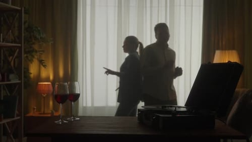 Vintage Record Player and Glasses with Red Wine on the Table Close Up A Young Couple is Dancing