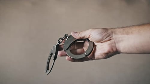 Hand Holds Handcuffs and Opens Them Close Up