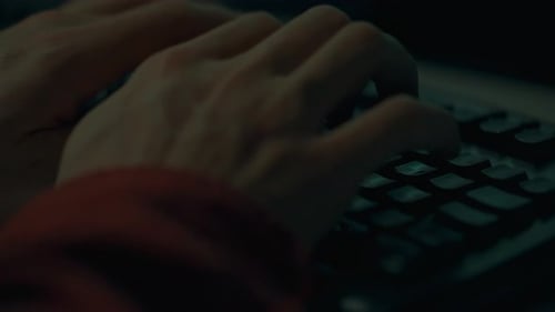 Ein Arbeiter schreibt nachts konzentriert Code auf einem tragbaren Laptop, seine Hände stehen im Mittelpunkt