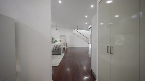 Open plan living room, dining room, and kitchen. Wooden floorboards in a white house