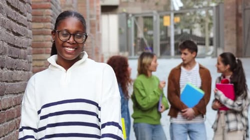 Cheerful Young Girl Smiling Confidently While Standing in Front of Her Friends in a Lively School