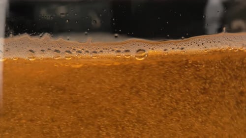 Cerveja light é colocada em um close-up de vidro. Bolhas de cerveja e espuma espirram na caneca. Refrescante