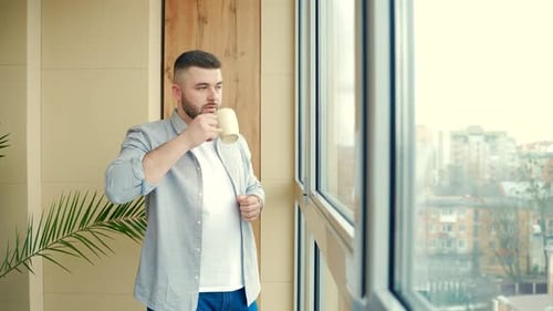 Bearded Man Drinking Coffee Near Window