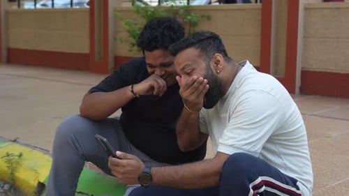 Two Men Watching Phone and Laughing Outside