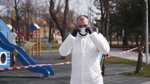 Man in Protective Suit Puts on Hood Outdoors