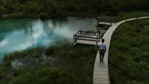 Man Walking Along Wooden Path at Zelenci Nature Reserve