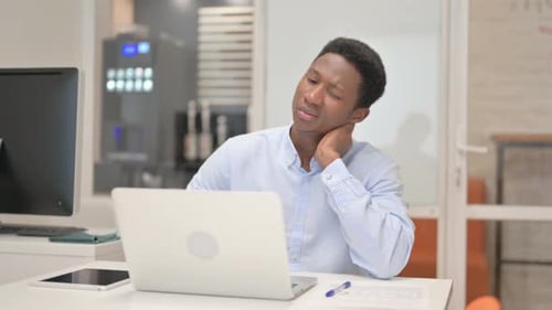 Young Adult Massaging Stiff Neck at Desk