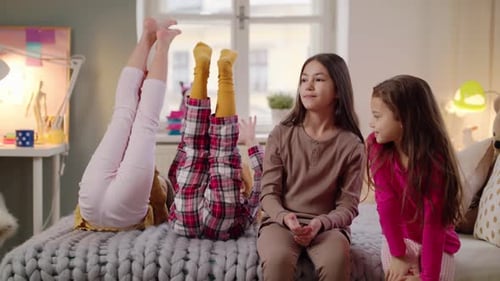 Girls in pajamas sitting on bed in bedroom