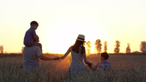 Excited Family Walks on Countryside Field at Back Sunset