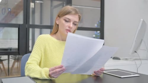 Young Blonde Woman Reading Documents at Work