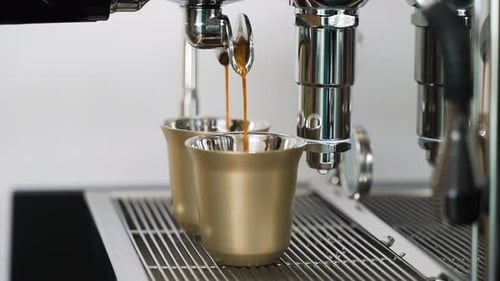 Espresso Being Poured Into Gold Colored Cups