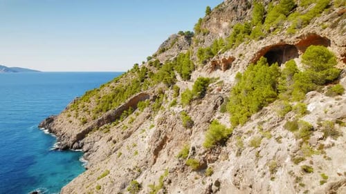 Sentier de montagne côtier rocheux avec des pins et des grottes menant au château d'Assos à Céphalonie, en Grèce