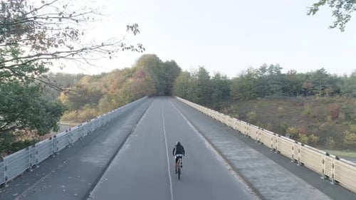 Behind drone shot of a mountainbike riding on an overpass.
