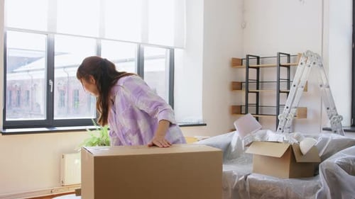 Woman Packing Belongings for Moving into Cardboard Box