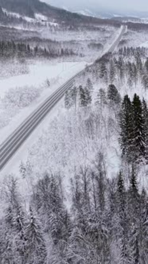 Aerial View Of Snowy Road Winding Through Winter Pine Forest