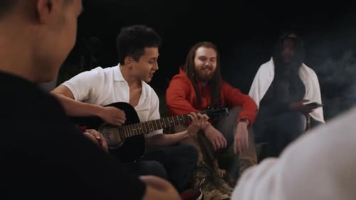 Friends Gathered Around Campfire, Playing Guitar at Night