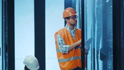 Technicians are Meticulously Working in the Server Room While Wearing Safety Gear for Protection