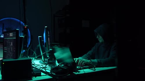 Hooded Hacker Coding in Dark Room at Night