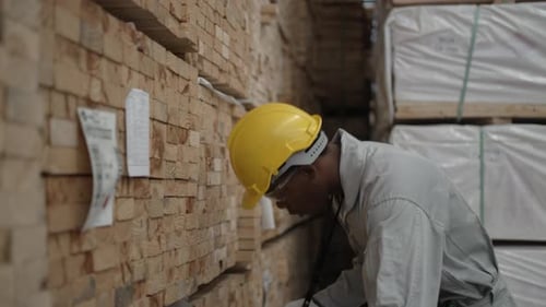 Fabrikarbeiter inspiziert gestapeltes Holz im Industrielager