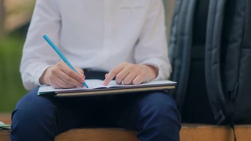 Focused Child Writes in Notebook Outdoors