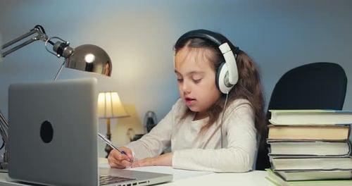 Girl Studying with Laptop and Headphones at Home