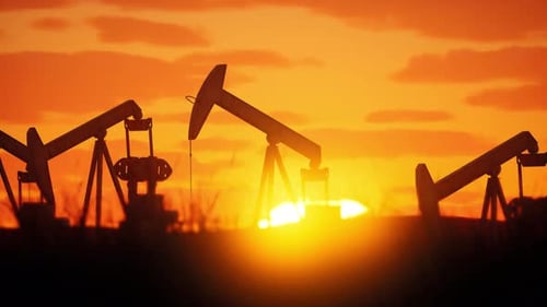 Ölpumpen arbeiten bei Sonnenuntergang in einem lebendigen Himmel